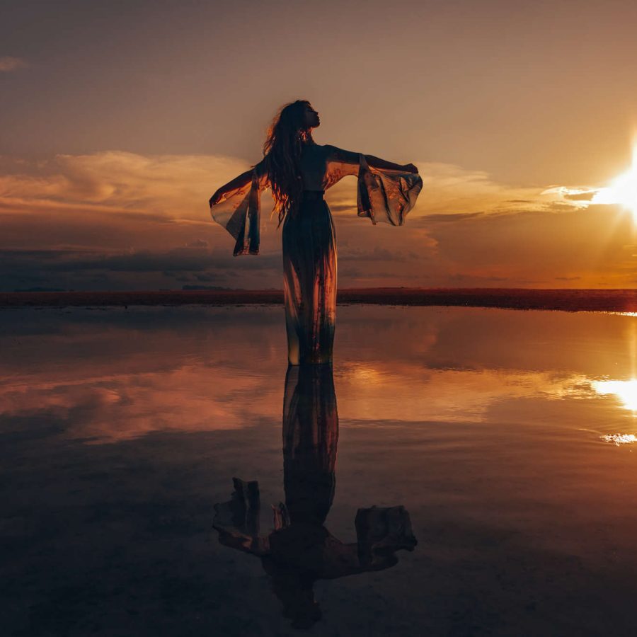 Frau steht im Wasser und streckt die Arme aus - symbolisiert das Gefühl von Freiheit.